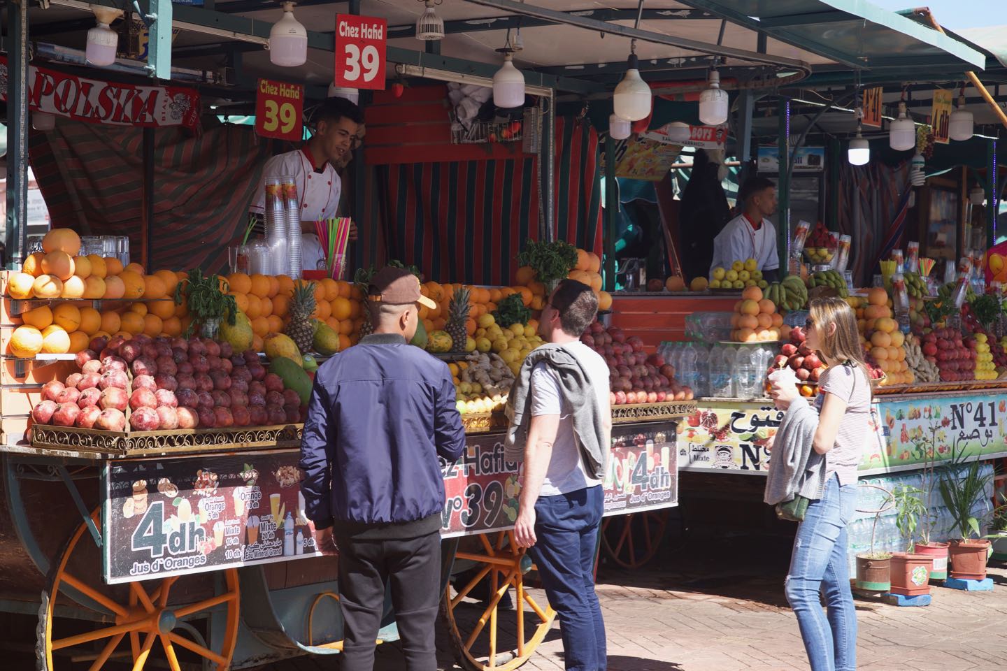 People buying juices on a food stall on Jemaa el-Fnaa durning daytime.